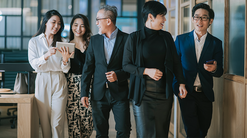 A diverse range of people pose against a grey background